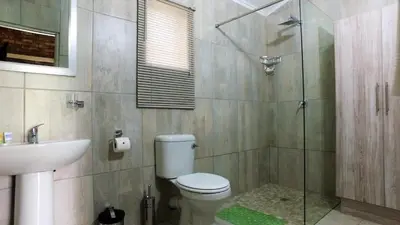 a bathroom with a toilet and a glass shower at Kruger's Guest House in White River