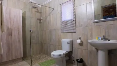 a bathroom with a shower and a toilet and a sink at Kruger's Guest House in White River