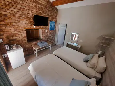 a bedroom with two beds and a brick wall at Kruger's Guest House in White River