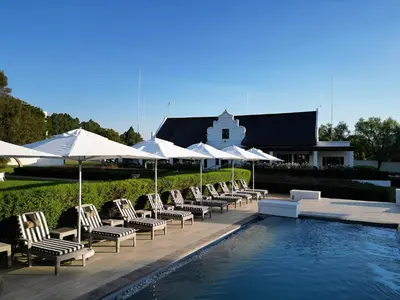 a row of chairs and umbrellas next to a swimming pool at Kievits Kroon Gauteng Wine Estate in Pretoria