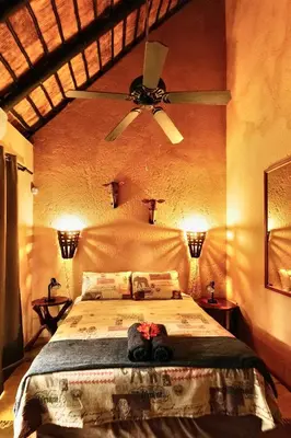 a bedroom with a large bed with a ceiling fan at Hyenas Call in Marloth Park