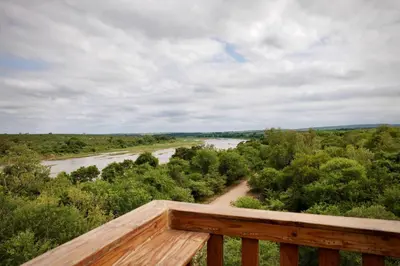 a view of a river from a wooden deck at Hyenas Call in Marloth Park