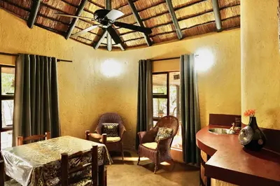 a living room with a ceiling fan and a table and chairs at Hyenas Call in Marloth Park