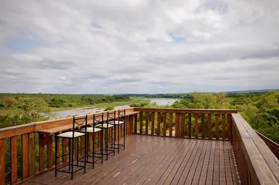 a row of chairs sitting on top of a wooden deck at Hyenas Call in Marloth Park
