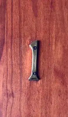 a metal key on top of a wooden table at Old Transvaal Inn Accommodation in Dullstroom