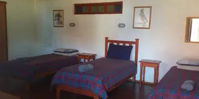 a bedroom with two beds and two stools in it at Old Transvaal Inn Accommodation in Dullstroom