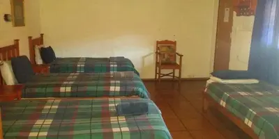 a room with two beds and a chair at Old Transvaal Inn Accommodation in Dullstroom
