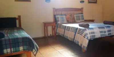 a bedroom with two beds and a table with a bedskirtspectspectspectspects at Old Transvaal Inn Accommodation in Dullstroom