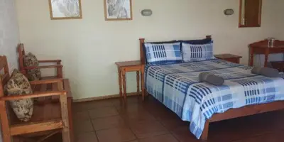 a bedroom with a blue and white bed and two chairs at Old Transvaal Inn Accommodation in Dullstroom
