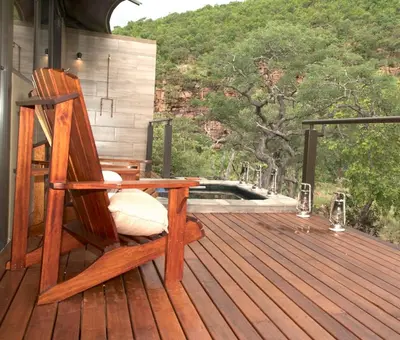 a rocking chair sitting on the deck of a house at Inzalo Safari Lodge in Welgevonden Game Reserve