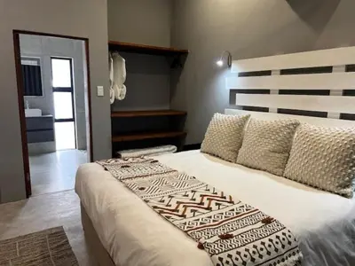 a bedroom with a large bed with pillows at Turaco Lodge - No Loadshedding in Marloth Park