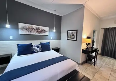 a bedroom with a large bed with blue pillows at Turaco Lodge - No Loadshedding in Marloth Park