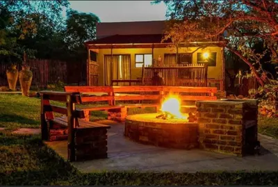 a fire pit in a yard with a bench and a house at Turaco Lodge - No Loadshedding in Marloth Park