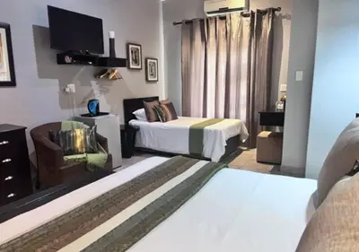 a hotel room with two beds and a tv at Turaco Lodge - No Loadshedding in Marloth Park