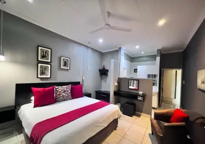 a bedroom with a large bed with red pillows at Turaco Lodge - No Loadshedding in Marloth Park