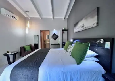 a bedroom with a large white bed with green pillows at Turaco Lodge - No Loadshedding in Marloth Park