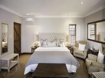 a bedroom with a large bed and two chairs at Bohemian Guesthouse - Pretoria in Pretoria