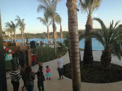 a group of people standing around in a resort with palm trees at The Blyde - Crystal Lagoon Penthouse Apartment in Pretoria