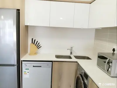 a kitchen with white cabinets and a sink and a dishwasher at The Blyde - Crystal Lagoon Penthouse Apartment in Pretoria