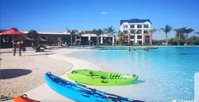 a green boat sitting on a beach next to the water at The Blyde - Crystal Lagoon Penthouse Apartment in Pretoria