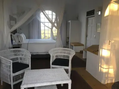 a bedroom with two wicker chairs and a bed at Ashbourne Country Escape Hazyview in Hazyview