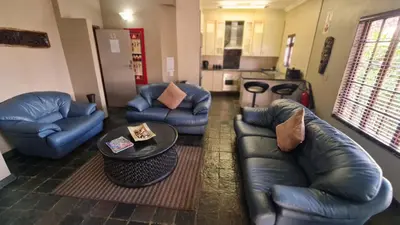 a living room with blue leather furniture and a table at Klein Bosveld Guest House in Witbank