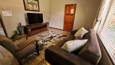 a living room with a couch and a tv at Klein Bosveld Guest House in Witbank