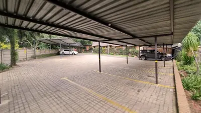 a parking lot with two cars parked in it at Klein Bosveld Guest House in Witbank