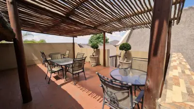 a patio with tables and chairs on a balcony at Klein Bosveld Guest House in Witbank