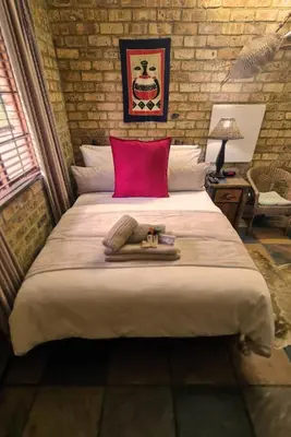 a bedroom with a large bed with a red pillow at Klein Bosveld Guest House in Witbank