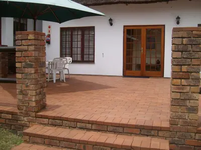 a patio with an umbrella and a table and chairs at Oaktree Lodge Guest House in Kyalami