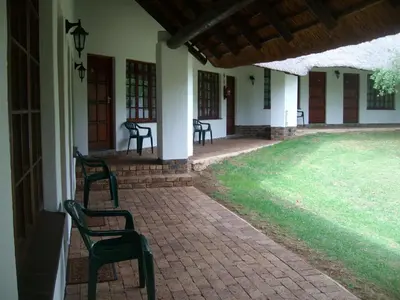 a group of chairs sitting on the porch of a house at Oaktree Lodge Guest House in Kyalami