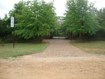 a driveway with trees and a gate in a park at Oaktree Lodge Guest House in Kyalami