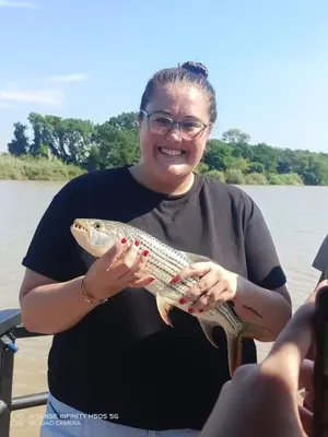 a woman holding a fish in her hands on a boat at Hippo Retreat & Tiger Fishing Komatipoort in Komatipoort