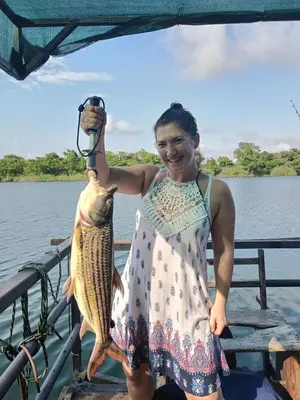 a woman holding a fish on a boat at Hippo Retreat & Tiger Fishing Komatipoort in Komatipoort