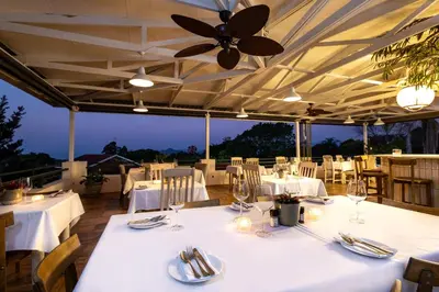 a restaurant with white tables and chairs and a ceiling at Shandon Lodge Guest House & Spa in Nelspruit