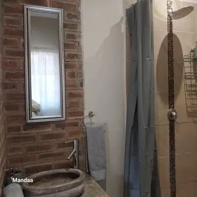 a bathroom with a stone sink and a mirror at Hhusha Hhusha in Malelane