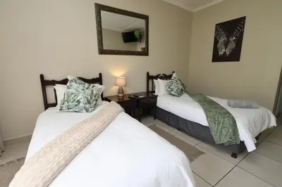 two beds in a room with a mirror at Hhusha Hhusha in Malelane