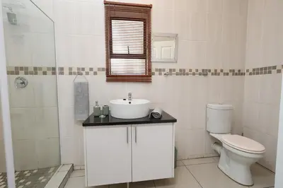 a white bathroom with a sink and a toilet at Hhusha Hhusha in Malelane