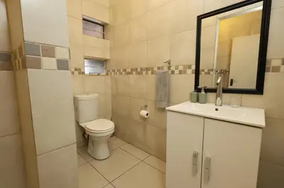 a bathroom with a toilet and a sink and a mirror at Hhusha Hhusha in Malelane