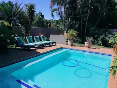 a swimming pool with two blue lounge chairs at Hhusha Hhusha in Malelane