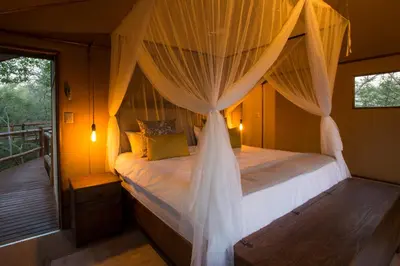 a bedroom with a canopy bed and a balcony at Vuyani River Lodge in Hoedspruit