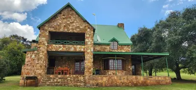 a large stone house with a green roof at Field and Stream in Dullstroom