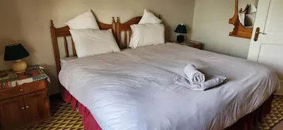 a bedroom with a large bed with white sheets and pillows at Field and Stream in Dullstroom