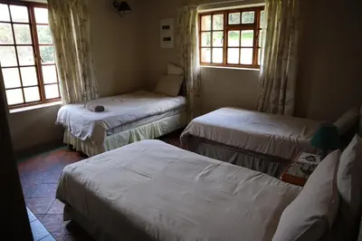 a room with three beds and two windows at Field and Stream in Dullstroom