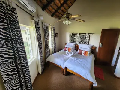a bedroom with two beds and a ceiling fan at Ditholo Game Lodge Bela Bela in Bela-Bela