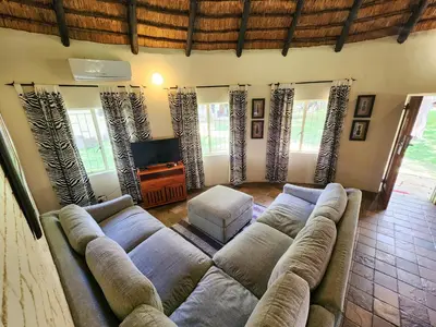 a living room with a large couch and a television at Ditholo Game Lodge Bela Bela in Bela-Bela