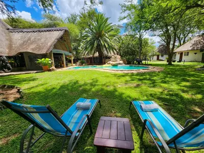 a yard with two chairs and a swimming pool at Ditholo Game Lodge Bela Bela in Bela-Bela
