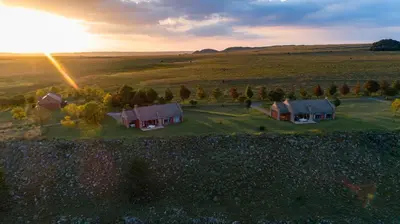 an aerial view of houses in a field with the sunset at Gooderson Kloppenheim Country Estate in Machadodorp