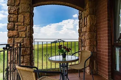 a patio with a table and chairs on a balcony at Gooderson Kloppenheim Country Estate in Machadodorp
